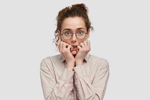 Person wearing glasses with fingers pressed against their mouth